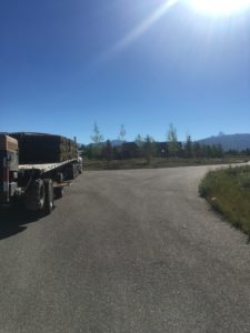 A flatbed semi truck loaded with sod going down the road.