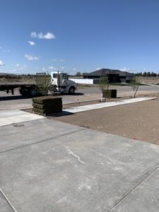 A dirt lawn ready for sod. Two pallets of sod have been unloaded from a flatbed semi truck and are waiting to be laid.