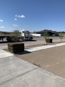 A dirt lawn ready for sod. Two pallets of sod have been offloaded from a flatbed semi truck and are waiting to be laid.